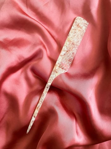 A comb on a pink satin cloth.